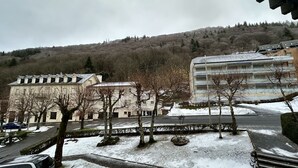Un edificio con techo plano y varias ventanas, rodeado de nieve en el suelo y árboles desprovistos de hojas.
