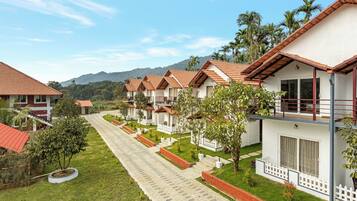 A row of bungalow-style accommodations with red-tiled roofs, white walls, and a paved pathway between them.
