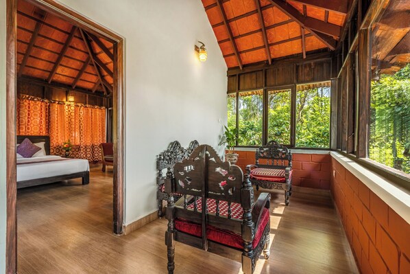 Une pièce avec un plafond en bois, un lit, une chaise et une fenêtre donnant sur un paysage verdoyant.