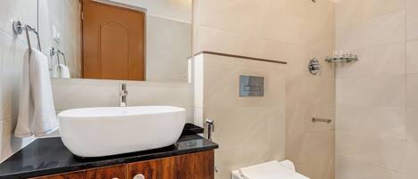 Un baño moderno con un lavabo grande blanco, un mueble de tocador de madera, un inodoro blanco y una zona de ducha.