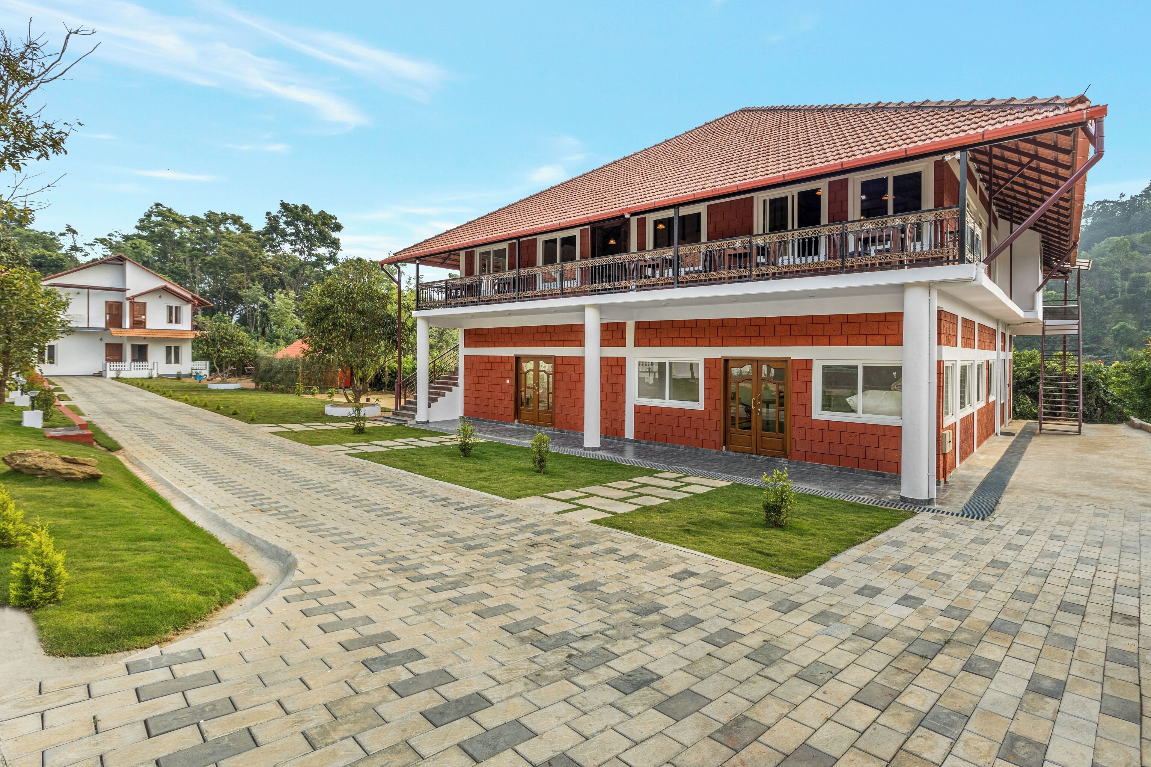 A two-story building with a red-tiled roof, a balcony with a railing, and a paved driveway.