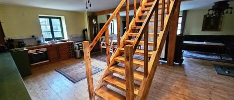 A spacious kitchen with wooden floors, a staircase, and a dining area.