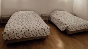 Ein Zimmer mit zwei Betten, Holzboden und sichtbaren Holzbalken an der Decke.