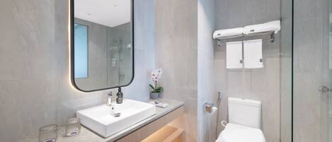 Uma casa de banho moderna com um espelho grande, lavatório branco e cabine de duche em vidro.