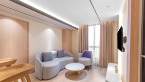 Una sala moderna con un sofá, un sillón, una mesa de centro y un televisor montado en la pared.