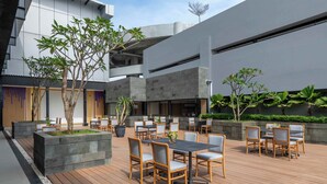 Un patio al aire libre con suelo de madera, mobiliario y plantas en macetas.