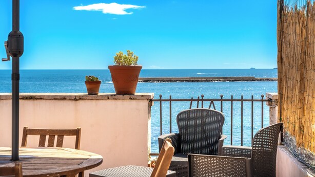 A terrace with a table and chairs, a potted plant, and a view of the sea. - Siracusa Horizon Home by Wonderful Italy (Syracuse)