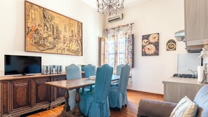 A living room with a wooden dining table, blue chairs, a television, and a large painting on the wall. - Siracusa Horizon Home by Wonderful Italy (Syracuse)
