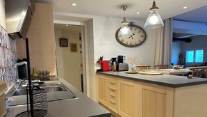 A modern kitchen with a central island, stainless steel appliances, and pendant lighting. - The Bamboo Lodge with its feet in the water (Anduze)