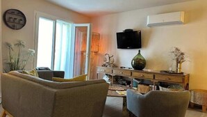 A living room with a sofa, chairs, a coffee table, a TV, and a cabinet. - The Bamboo Lodge with its feet in the water (Anduze)