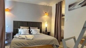 A bedroom with a bed, bedside lamps, and a wooden headboard. - The Bamboo Lodge with its feet in the water (Anduze)