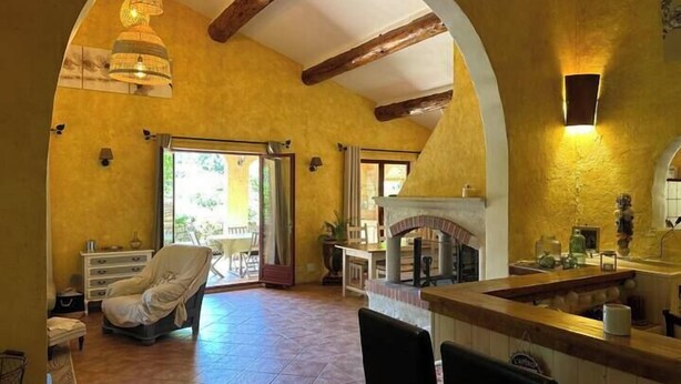 A spacious living area with a fireplace, a dining area, and a large arched doorway leading to an outdoor patio. - Beautiful Cevennes farmhouse with swimming pool (Corbès)
