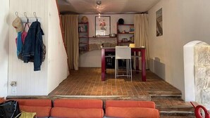 Una habitación acogedora con un sofá rojo, una mesa de comedor y una zona de cocina.
