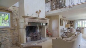 A spacious living room with a stone fireplace, a high ceiling, and a balcony. - Le mas d'Elise, in the heart of the Cévennes countryside (Saint-Hippolyte-de-Caton)