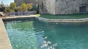 A swimming pool with a stone building in the background. - Village house with swimming pool (Saint-Étienne-de-l'Olm)