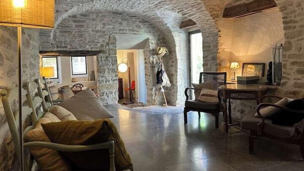 A rustic stone interior with a cozy seating area, a fireplace, and a dining table. - Village house with swimming pool (Saint-Étienne-de-l'Olm)