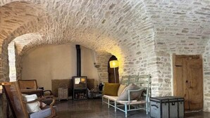 A rustic interior with stone walls, a fireplace, and traditional furniture. - Village house with swimming pool (Saint-Étienne-de-l'Olm)