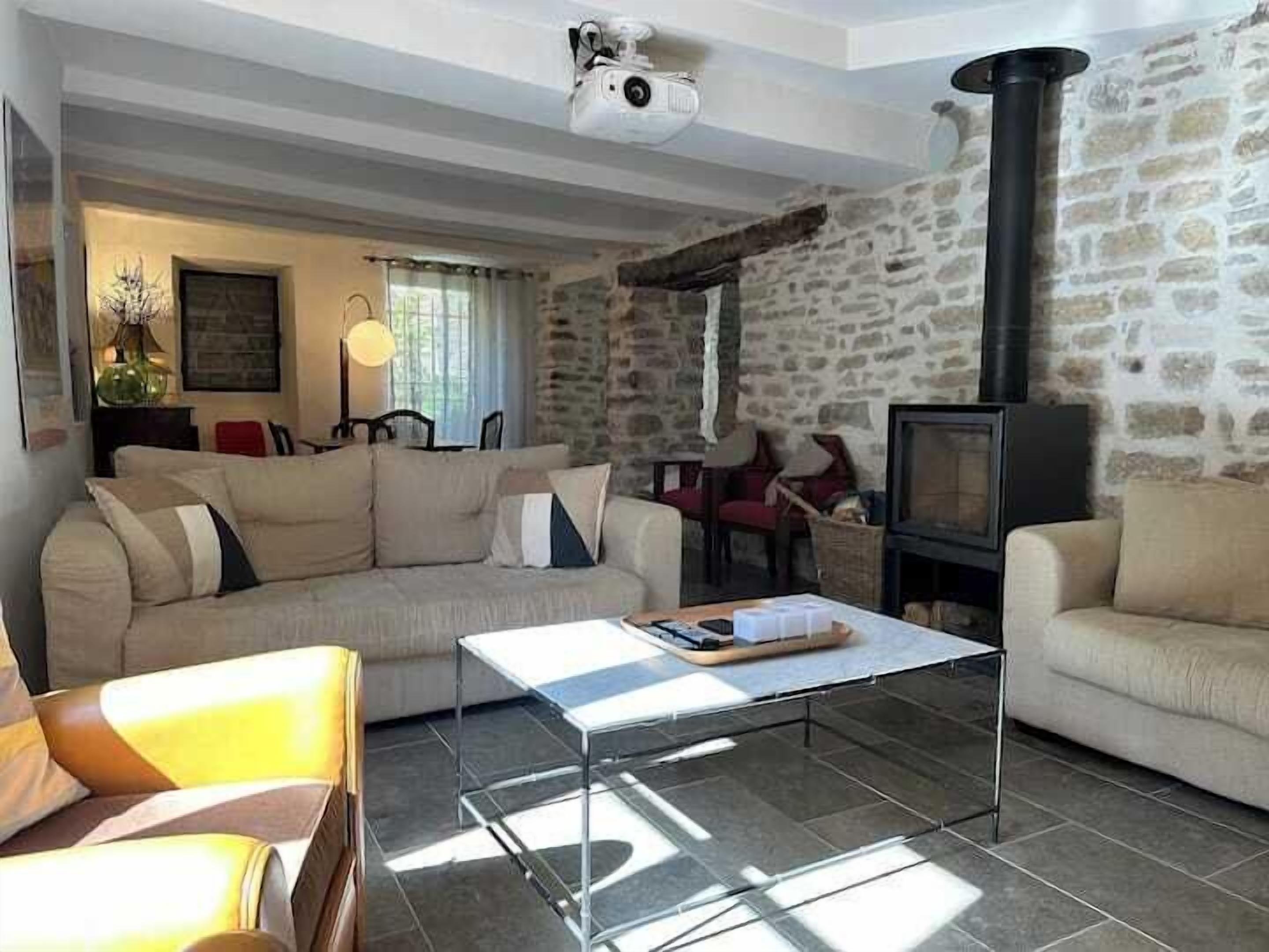 Un salon chaleureux avec un mur en pierre, un canapé, une table basse et une cheminée.