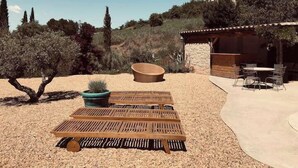 An outdoor patio area with a wooden table and chairs, a large terracotta bowl, and a potted plant. - Le mas du figuier at the foot of the medieval city (Vézénobres)