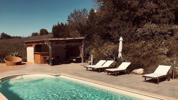 A swimming pool with clear water, surrounded by lounge chairs and a small structure with a roof. - Le mas du figuier at the foot of the medieval city (Vézénobres)