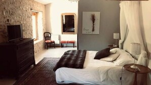 A bedroom with a bed, a dresser, a chair, a mirror, and a painting on the wall. - Le mas du figuier at the foot of the medieval city (Vézénobres)