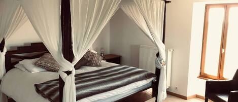 A four-poster canopy bed with white drapes, a striped bedspread, and multiple pillows.
