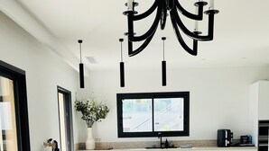 Una cocina moderna con una isla central, una zona de comedor con mesa de madera y un amplio ventanal que proporciona luz natural.