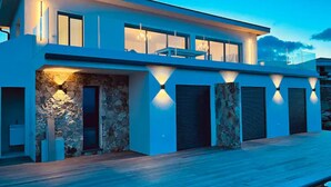 Una casa moderna de dos pisos con fachada de piedra, ventanas amplias y una terraza de madera.