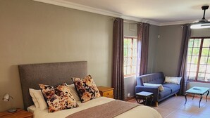 A bedroom with a large bed, a nightstand, a dresser, a sofa, and a small table. - Charming villa with WiFi in Gillitts (Gillitts)