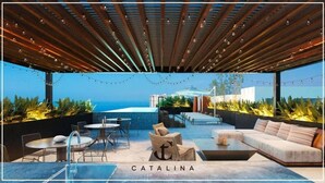 Um pátio externo com piscina, áreas de estar e vista para o oceano.