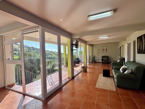 A spacious living area with a balcony, a green sofa, and a tiled floor. - Green House | Mountain Green Views & Sea Glimpse | Calheta (Calheta)