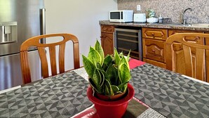 A kitchen with wooden cabinets, a stainless steel refrigerator, a microwave, and a dishwasher. - Green House | Mountain Green Views & Sea Glimpse | Calheta (Calheta)