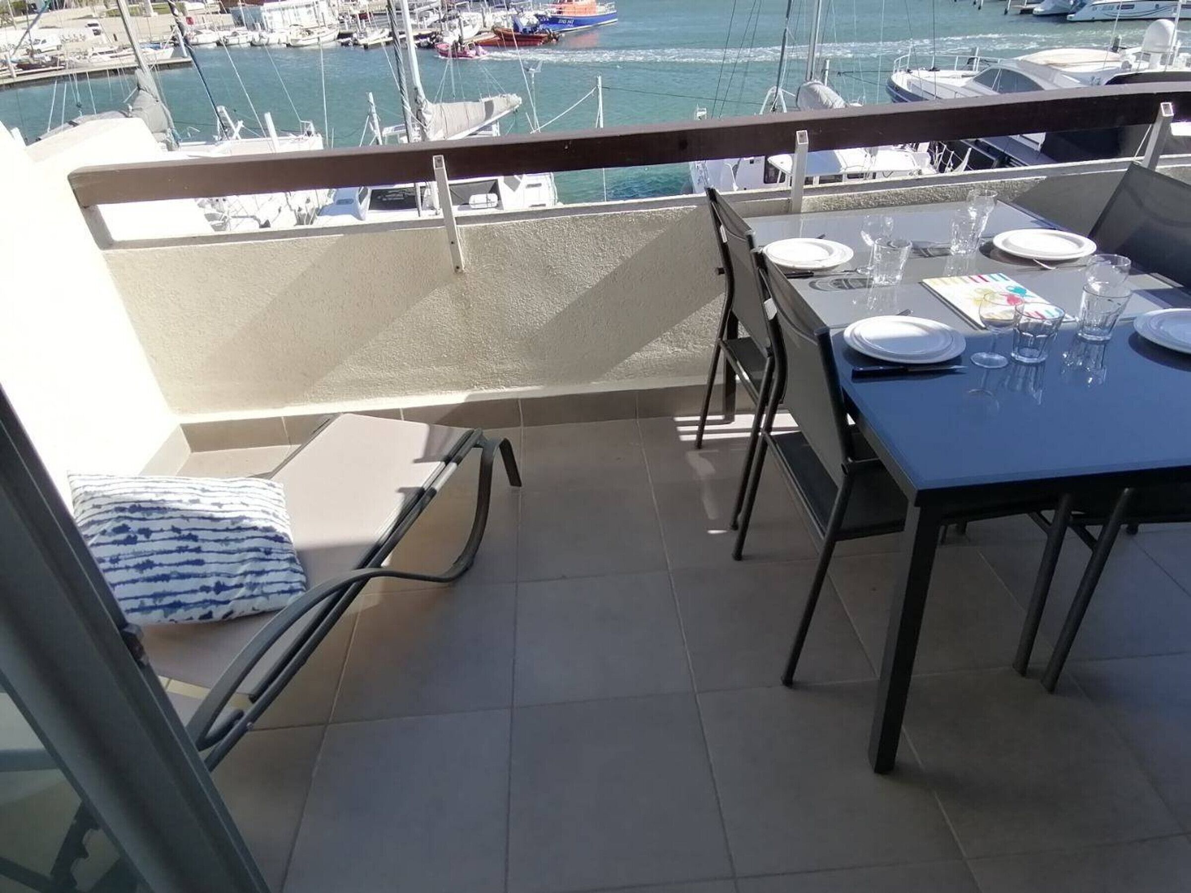 Een balkon met een eettafel, met uitzicht op een jachthaven met boten.