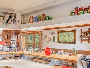 Una cocina con una encimera amplia, diversos alimentos y una ventana con vistas a árboles.