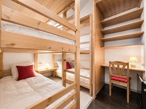 Une chambre avec des lits superposés, un bureau et une chaise.