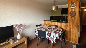 A compact living space with a dining area, a television, and a wooden accent wall. - Apartment on the slopes in Super Besse (Besse-et-Saint-Anastaise-Super Besse)