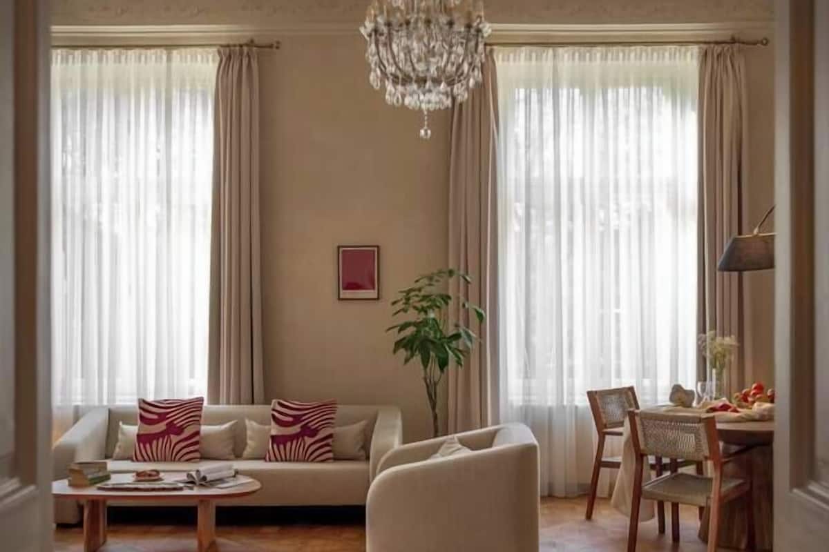 Un salón espacioso con una araña, un sofá, una mesa de centro y un comedor con sillas y una mesa.