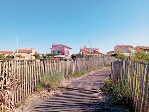 Uma trilha de paralelepípedos leva a uma fileira de casas com um cercado de madeira de um lado.