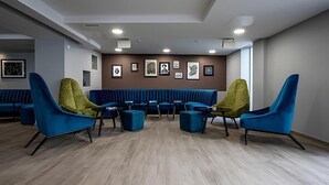 A modern lounge area with blue and green chairs, a blue sofa, and a wooden floor. - Liv Student Dublin (Dublin)