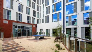A modern building with multiple floors, large windows, and a courtyard with a ping pong table. - Liv Student Dublin (Dublin)