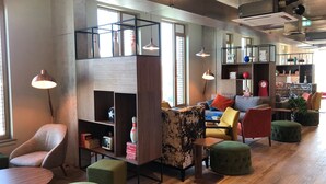 A modern interior with a loft-style seating area, a wooden coffee table, and a bookshelf with various items. - Liv Student Dublin (Dublin)