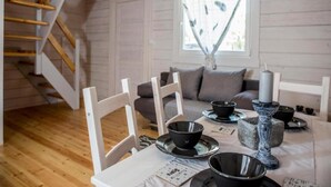 Ett mysigt rum med en trätrappa, en soffa och ett matbord dukat med svarta skålar och ett ljus.