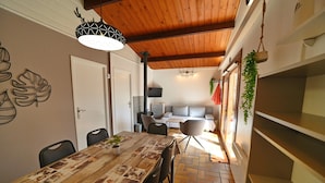 A dining area with a wooden table, chairs, a potted plant, and a ceiling with exposed beams. - Chalet in Viroinval Near Nature Park (Viroinval)