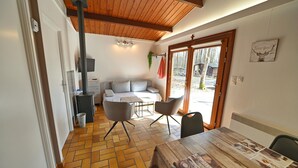 A room with a wooden ceiling, a sofa, two chairs, a table with a patterned tablecloth, and a door leading outside. - Chalet in Viroinval Near Nature Park (Viroinval)