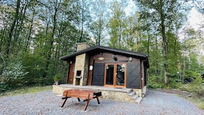 Eine rustikale Holzhütte mit Steinfassade, Holzläden und einer Bank davor.