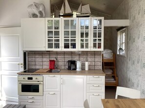 A compact kitchen with white cabinetry, a built-in oven, a coffee maker, and a sink. - 3 Person Holiday Home in Solvesborg (Sölvesborg)