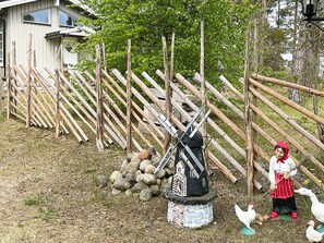 A rustic outdoor scene with a windmill, a statue of a figure with a red hat, and a wooden fence. - 3 Person Holiday Home in Solvesborg (Sölvesborg)