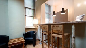 Une cuisine compacte avec un comptoir-bar en bois, une chaise noire, une petite table en bois et un radiateur.