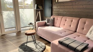 Una sala de estar moderna con un sofá rosa, una mesita auxiliar y una lámpara de pie.