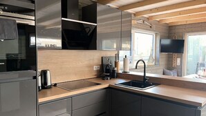 Una cocina moderna con armarios de madera, encimera negra, un lavamanos y una estufa empotrada.